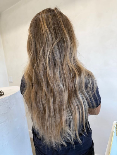 Long wavy blonde balayage with a soft grown out root at Shade Studio in Long Branch, New Jersey