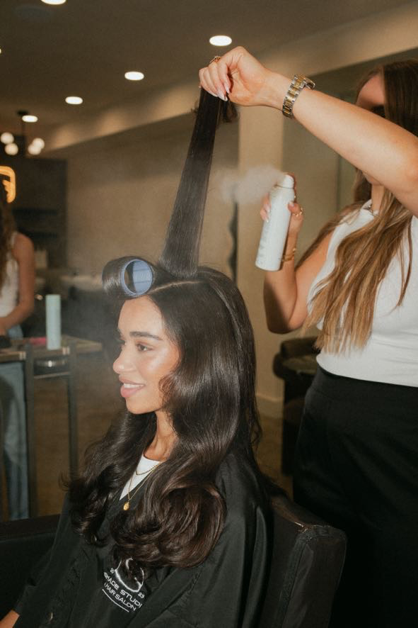 Stylist holding a hand tied weft against a client's own hair to match color at Shade Studio in Long Branch, New Jersey